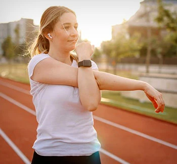 Woman stretching to exercise outdoors with Apple Watch