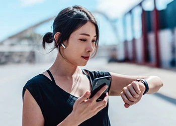 Woman using iPhone and Apple Watch outside