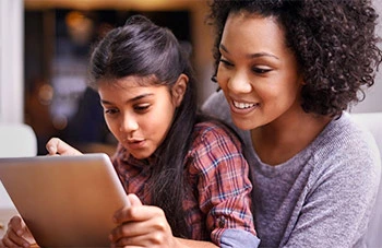 Mom watching daughter playing on tablet