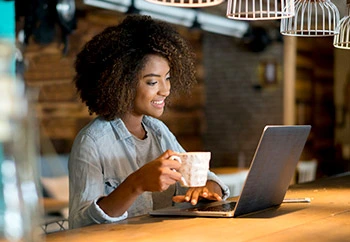 Black woman using public Wifi on laptop in coffee shop